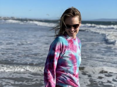 Cassidy Boesch has her shades on as she is smiling and walking.